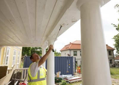 Stefan som petar loss en bit av färg, när han undersöker ett bristfälligt måleri
